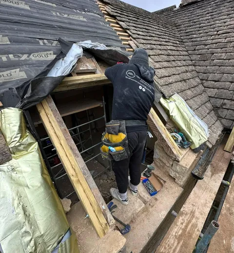 One of the team in an F&H Construction top, fitting timber around a new dormer opening on a stone slate roof.