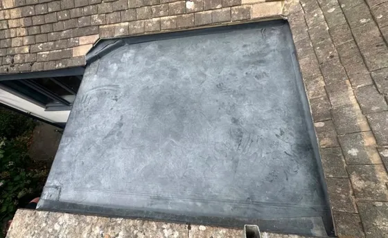 A lead flat roof laid between stone slate slopes, dressed up to the tiles around it.