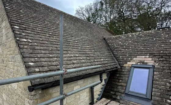 A rooflight set into a Cotswold stone slate roof, with the slates cut round it and flashed to the sides.